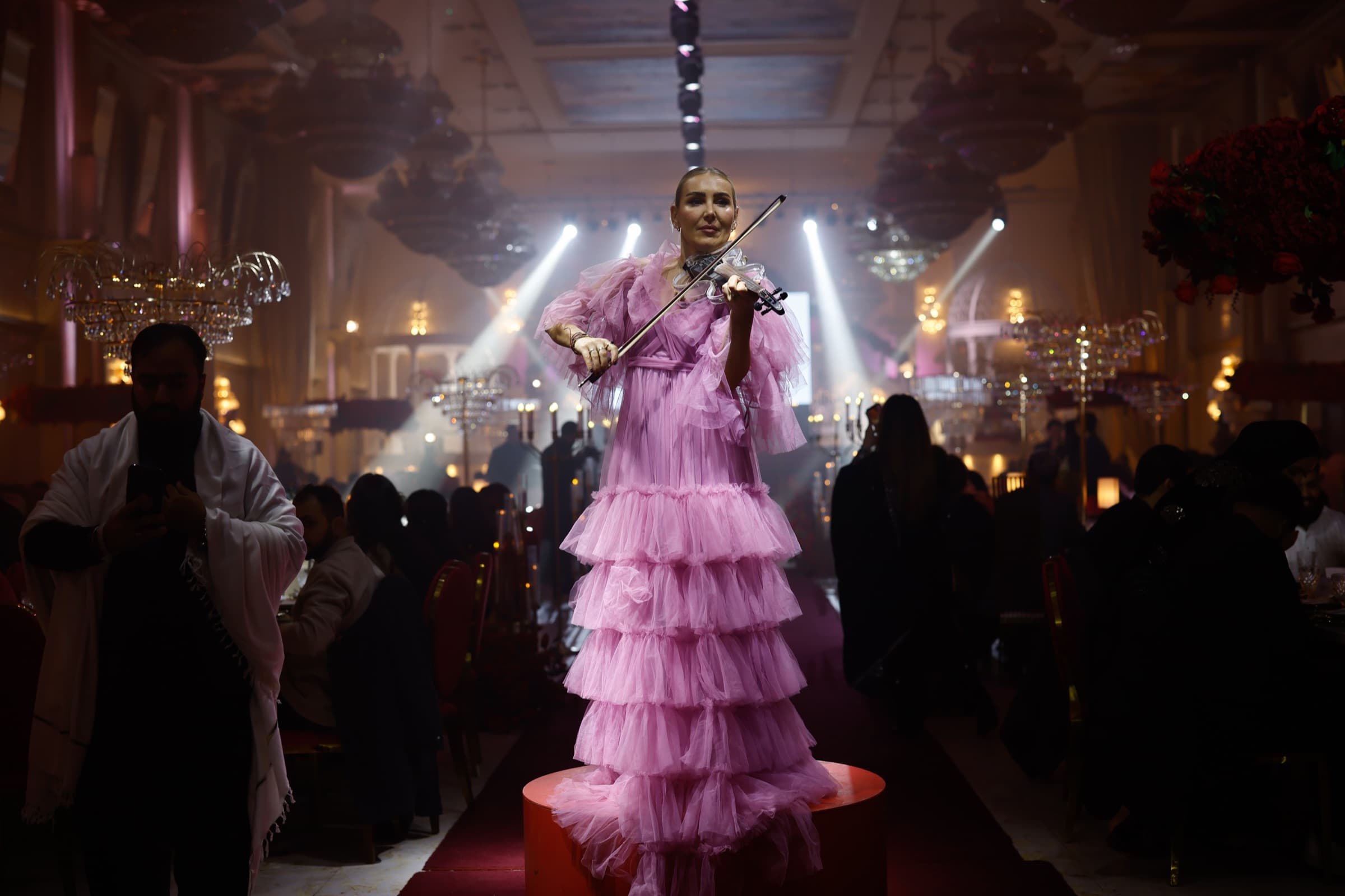 Violinist in a pink tulle gown performing among the tables